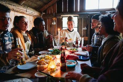 Male and female friends talking while having meal in cottage