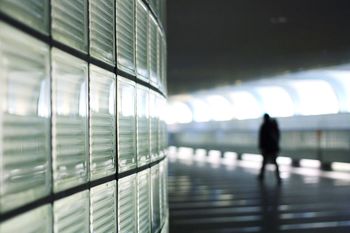 Silhouette of person walking with glass wall in foreground