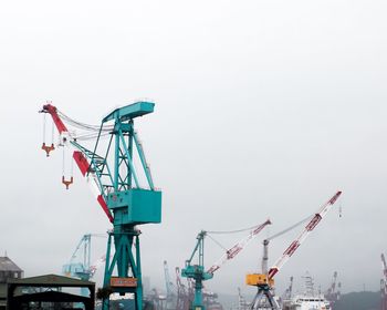 Low angle view of cranes against sky