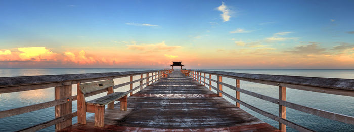 Pier over sea against sky during sunset