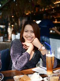 Portrait of a smiling young woman sitting at restaurant table