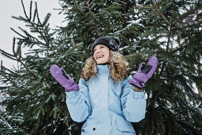 Hello winter, happy wintertime. happy young curly woman with hands raised up celebrating winter