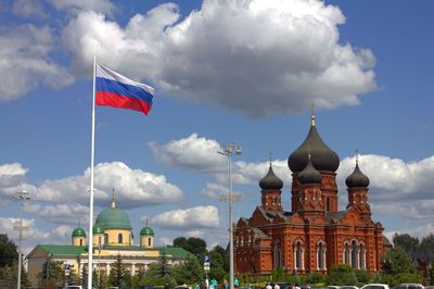 Low angle view of flags on building against cloudy sky