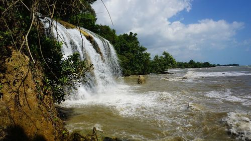 Scenic view of waterfall against sky