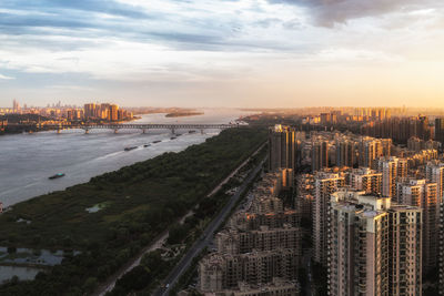 High angle view of city buildings against cloudy sky