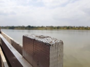 Close-up of wooden post by lake against sky