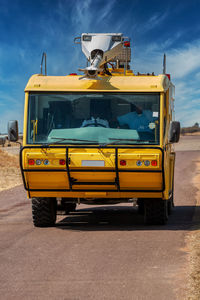 Yellow bus on road against sky