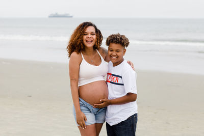 Brother posing with pregnant sister on beach