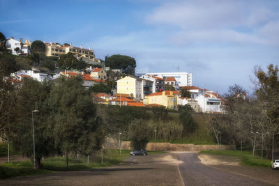 Road amidst buildings in town against sky