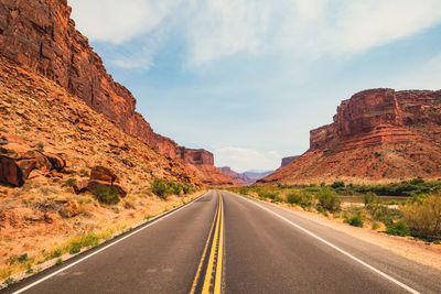 Road leading towards mountains against sky