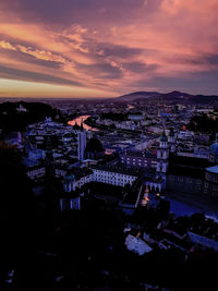 High angle view of illuminated city against sky at sunset