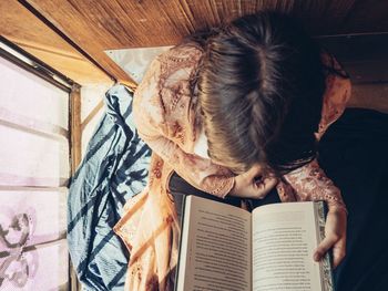 High angle view of woman reading book at home