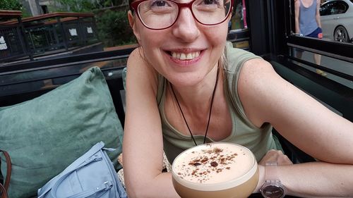 Portrait of a smiling young woman drinking glasses