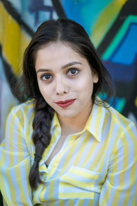 Portrait of smiling young woman against graffiti wall