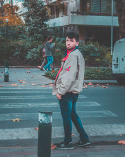 Portrait of young woman standing on street in city