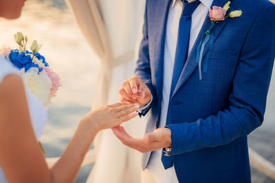 Midsection of couple holding flower bouquet