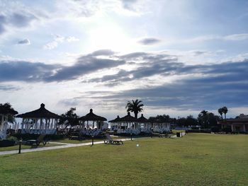 Built structure on field by houses against sky