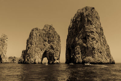 Rock formation in sea against clear sky