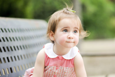 Close-up of cute baby girl looking away while sitting on bench