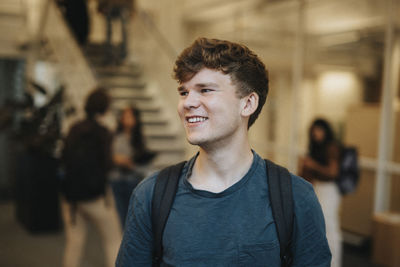 Happy young male student standing in university