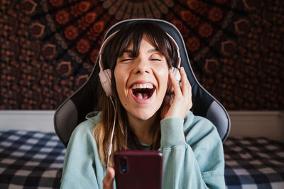 Young woman listening music against wall