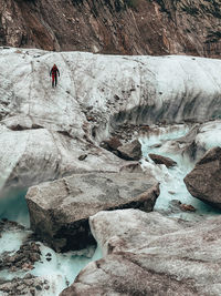 Female hiker crossing melt-water river on glacier in chamonix