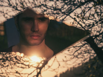 Reflection of man on broken mirror against trees