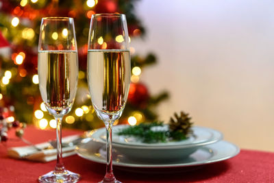 Close-up of wineglasses on table against christmas tree