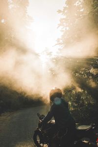 Silhouette man riding motorcycle on road in forest