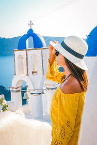 Woman in hat standing by church in city