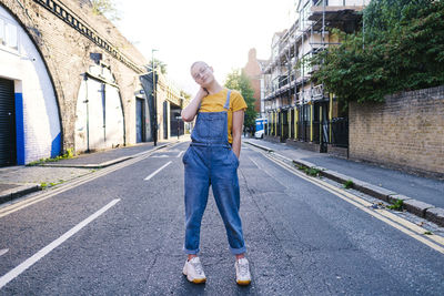 Non-binary person with hand in pocket standing on road