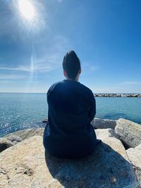 Rear view of man looking at sea against sky