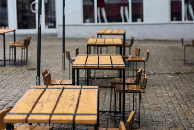 Empty chairs and tables at sidewalk cafe against building