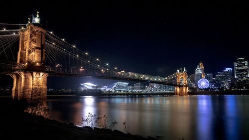 Illuminated bridge over river at night