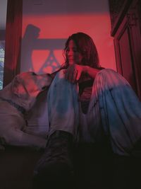 Young adult woman looking at her dog lovingly in pink lighting indoors  