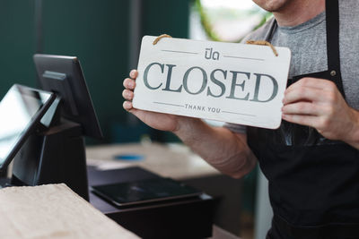 Midsection of barista showing close sign