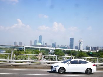 Cars on road in city against sky