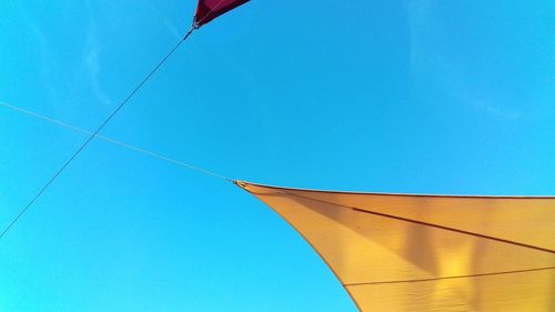 Low angle view of yellow parasol blue sky