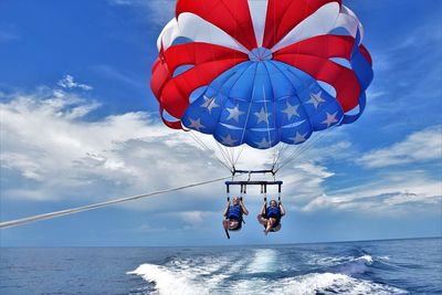 Women parasailing over sea against sky