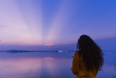 Side view of woman looking at sea against sky