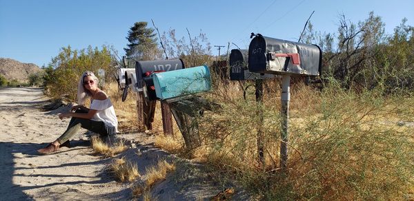 A young woman and mailboxes on a dirt road in the california desert