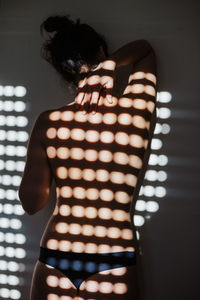 Rear view of woman standing against illuminated wall