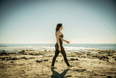 Full length of young woman standing at beach