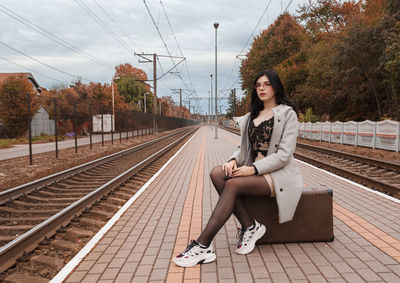 Full length of woman sitting on railroad station platform