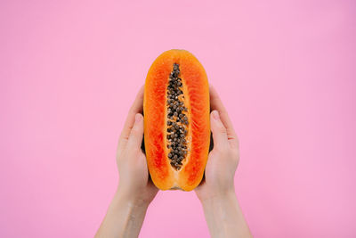 Person holding apple against pink background