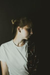 Portrait of a young woman looking away over black background