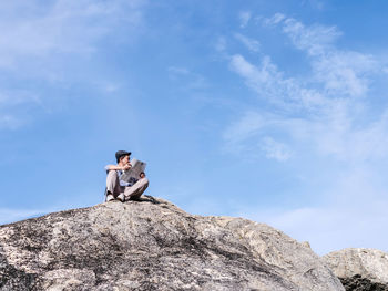 Low angle view of man sitting on rock