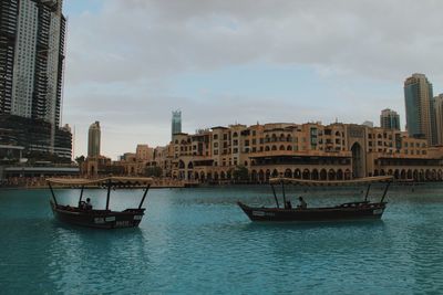 Boat sailing on sea against sky in city