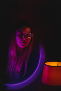 Portrait of young woman against black background