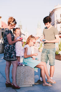 Mother and children having ice cream in city during sunny day